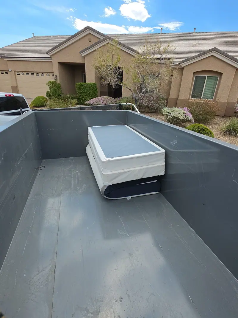 A box spring in the empty dump trailer outside a stucco home