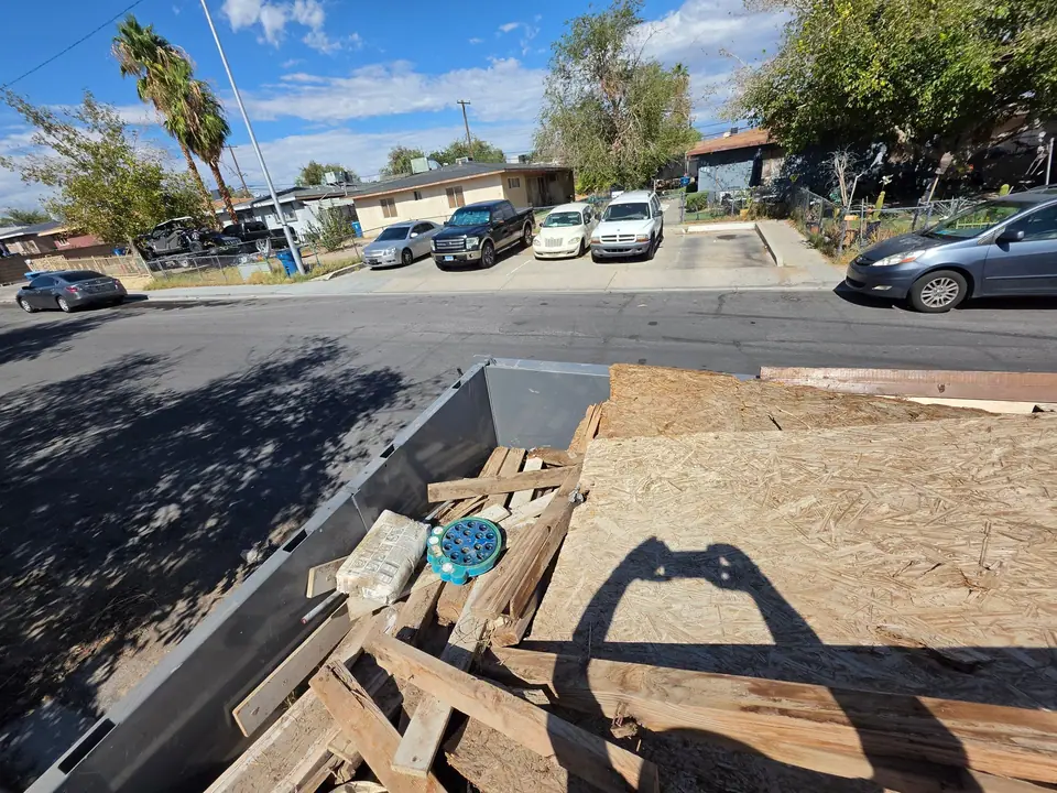 Scrap lumber and plywood loaded in the Legend Hauling dump trailer on a residential street