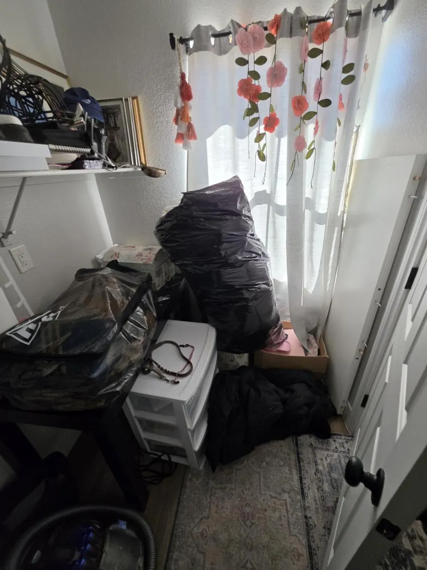 Black bags, plastic drawers and bins piled by a bedroom window