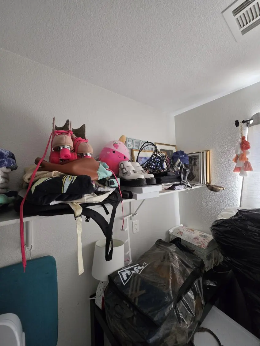 Laundry nook packed with bags, stuffed toys and clutter on and under the shelf