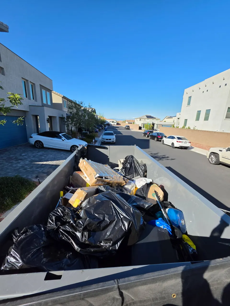 Dump trailer loaded with black trash bags and cardboard on a residential street