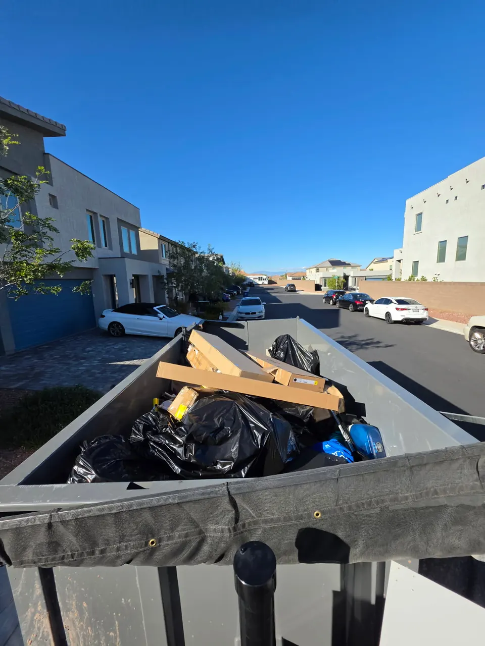 Dump trailer full of black bags and scrap lumber beside new townhomes
