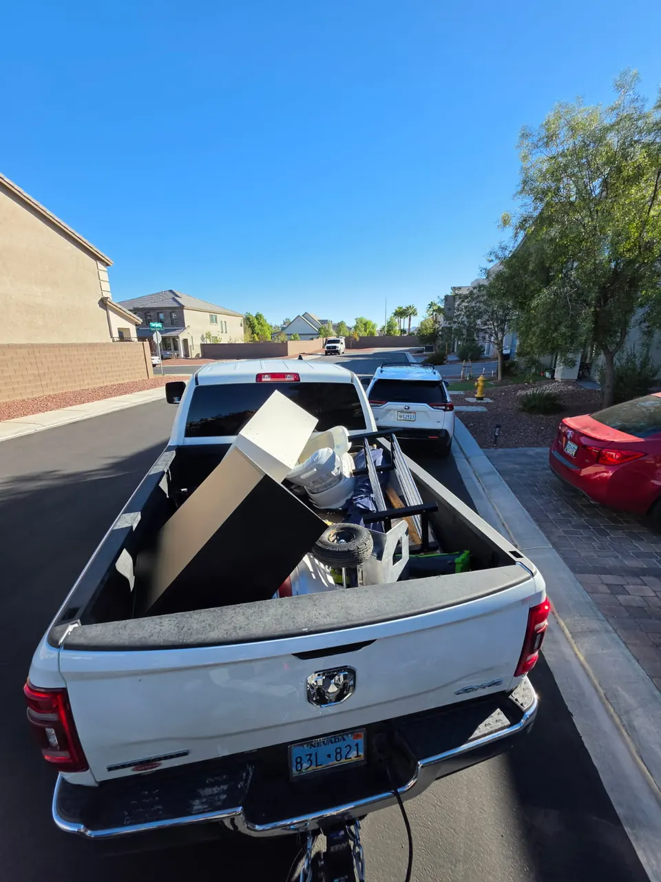 White pickup with the bed loaded with a cabinet and household junk on a residential street