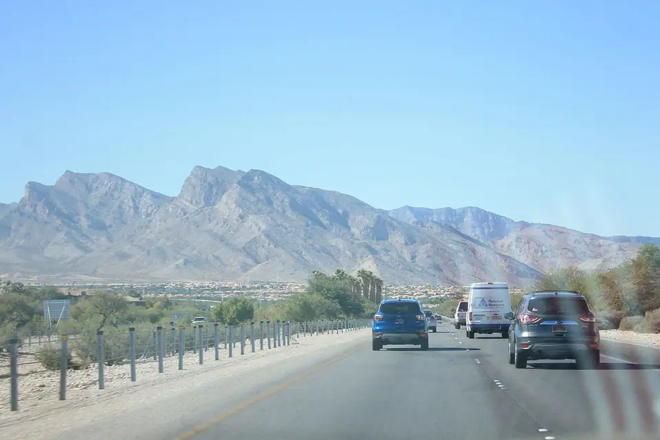 Red Rock Canyon peaks above a suburban road and housing along Summerlin Parkway, daylight, Summerlin, NV